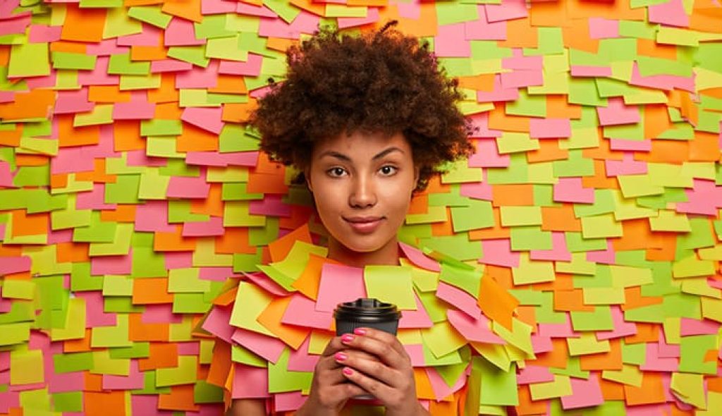 serious-looking-ethnic-office-worker-has-coffee-break-holds-takeout-beverage-hands-looks-directly-camera-talks-with-colleague-poses-indoor-against-adhesive-notes-wall-people-drinking